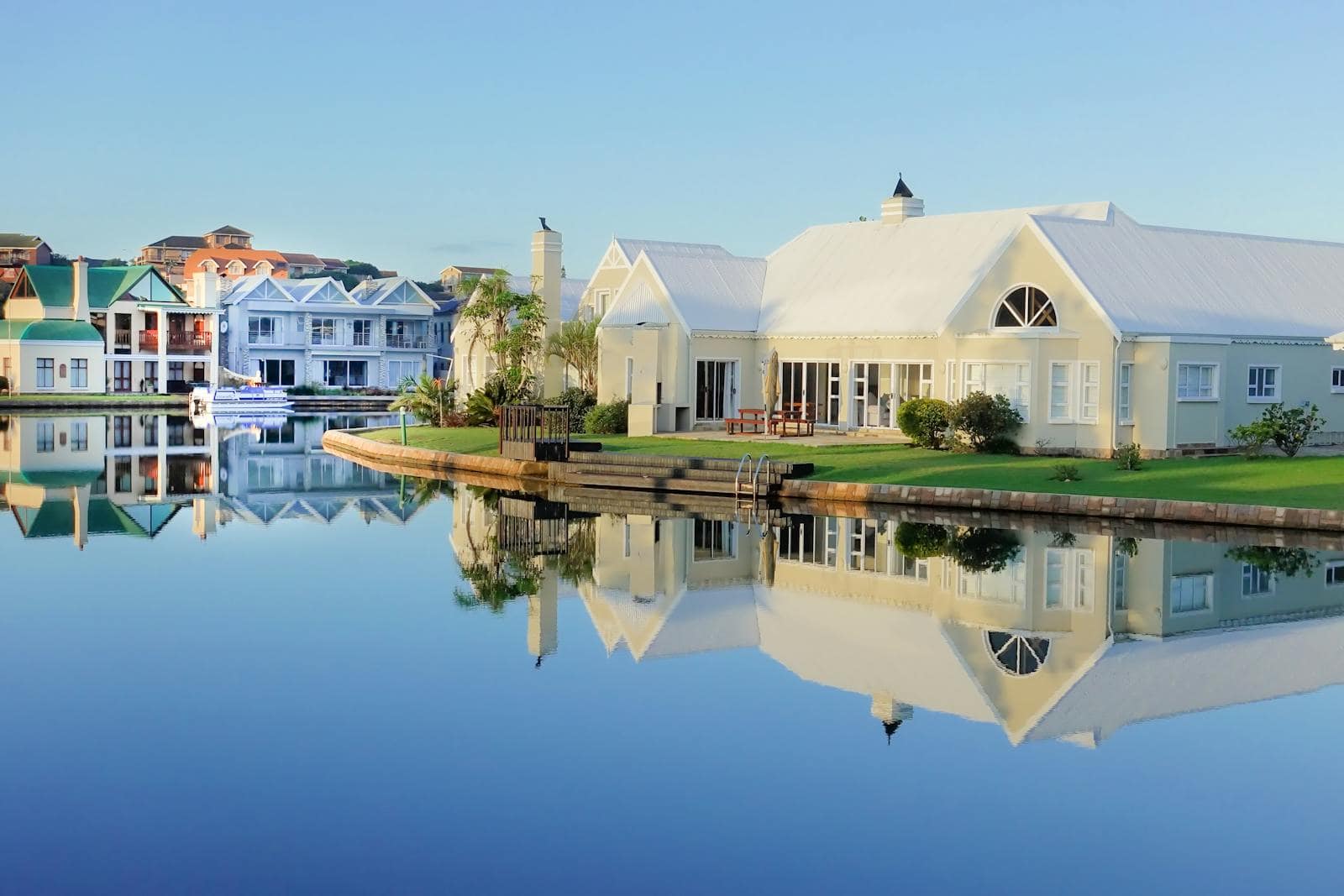 Serene view of elegant waterfront villas with perfect reflection on calm water.