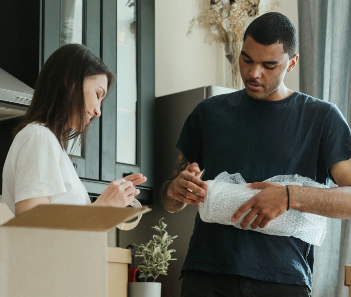 Couple unwrapping items from moving boxes into their new home