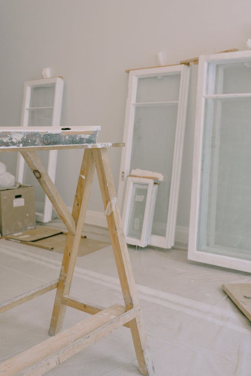 A room under renovation featuring windows and construction tools.
